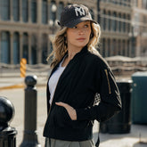 Woman wearing a black jacket and NY baseball cap on a city street