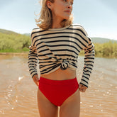 Front view of red Almost Cheeky Bottoms with cheeky coverage worn by a model in shallow water