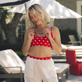 Front view of red Rise Bikini Top, Star showcasing its white star pattern on a model by a pool