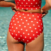 Rear view of red Star High-Waisted Bottoms showcasing white star print and high-waisted fit on model by pool