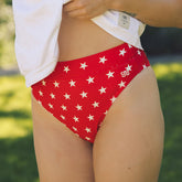 Side view of Star Almost Cheeky Bottoms showcasing a red star print and cheeky fit on a model outdoors