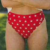 Front view of red star-print Almost Cheeky Bottoms showcasing cheeky fit on a model against a blurred outdoor background