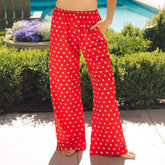 Front view of red Slip On Trouser, Star showcasing wide-leg fit, elastic waistband, pocket, and white star pattern by a pool