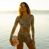 Front view of desert camo boy shorts showcasing the patterned fabric on a model by the water