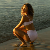 Rear view of Braid Bandeau showcasing its lavender houndstooth pattern and fit on a model with ocean water in the background