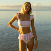 Front view of Lavender Houndstooth Bella Crop Top showcasing ruffled straps and square neckline on a model by the water