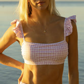 Front view of lavender houndstooth Bella crop top showcasing ruffled shoulder straps and a fitted square neckline with water background