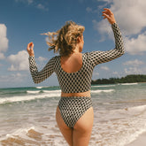 Rear view of Kona Almost Cheeky Bottoms showcasing a black and cream geometric pattern on a model at the beach