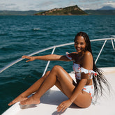 Three-quarter view of Sea Glass Almost Cheeky Bottoms showcasing the cheeky fit on a model seated on a boat over the ocean