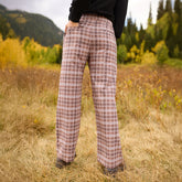 Rear view of Audrey Trouser, Toffee Plaid showcasing the plaid pattern and wide-leg fit on a model in a grassy field