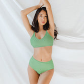 Front view of green high-waisted bottoms on a model showcasing the high-rise fit against a white draped background
