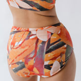 Rear view of Pixie High-Waisted Bottoms with bright multicolor abstract print and high-waisted fit on model, white background