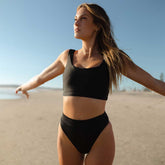 Front view of black Almost Cheeky Bottoms showcasing cheeky coverage on a model at the beach