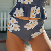 Close-up front view of Daisy High-Waisted Bottoms showcasing a navy floral print with white and orange flowers on a model