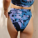 Rear view of Hibiscus Almost Cheeky Bottoms showing blue and lavender floral print on model against a neutral background