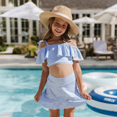 Front view of Kids Swim Skirt in Sand Bar Blue on a child, showcasing blue and white stripes by a pool