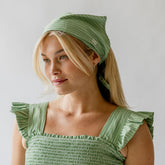 Front view of green and white striped bandana worn as a headscarf on a model against a light gray background