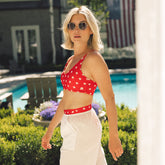 Three-quarter view of the red Rise Bikini Top, Star with white star print and thin straps on a model beside a pool