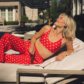 Front view of red Rise Bikini Top showcasing white star print on a model relaxing outdoors