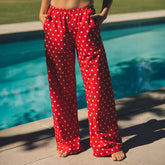 Front view of Slip On Trouser, Star showcasing red star print and wide legs with poolside background