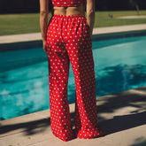 Rear view of the red Slip On Trouser, Star showcasing its white star pattern and wide-leg fit beside a pool