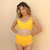 Front view of Rise Bikini Top in Golden Terry showcasing its scoop neckline and wide straps on a model against a beige background