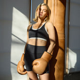 Front view of the black Double Exhale Bra showcasing white dotted trim on a model with boxing gloves indoors