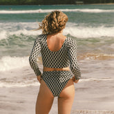 Rear view of Kona Almost Cheeky Bottoms showing black and white geometric pattern and almost cheeky fit on model by ocean