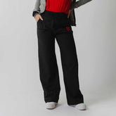 Front view of black Utah Audrey Trouser on a model, showing wide-leg fit, drawstring waist, side pockets, and red emblem