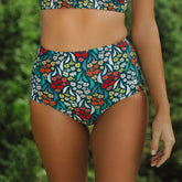 Front view of Costa Floral High-Waisted Bottoms showcasing a colorful floral pattern with a blurred green background