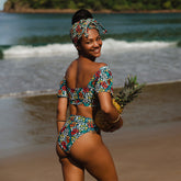 Rear view of Costa Floral Almost Cheeky Bottoms in a colorful floral pattern on a model at the beach