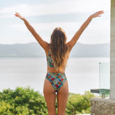 Back view of Costa Floral Almost Cheeky Bottoms showcasing dark teal floral print and cheeky fit on model with lake background