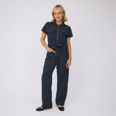 Front view of City Jumpsuit, navy pinstripe, showcasing short sleeves, zip front, and tie waist on a model