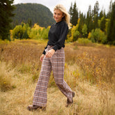 Side view of the Audrey Trouser in Toffee Plaid showcasing its wide-leg fit on a model in a mountain meadow