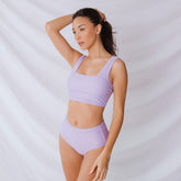 Front view of periwinkle high-waisted bottoms showcasing the high-rise fit on a model against a light draped background