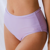 Close-up side view of periwinkle high-waisted bottoms showcasing smooth fabric and logo detail on a model