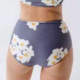 Close-up front view of Daisy High-Waisted Bottoms showcasing a high waist and white floral print on a blue-purple background
